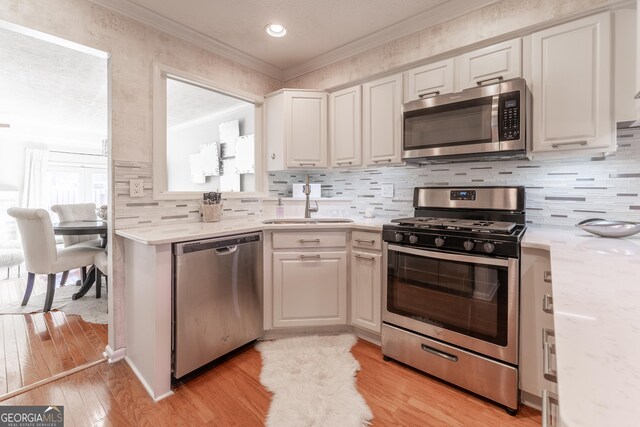 111 Swanton Hill Ct, Decatur, GA 30030 - kitchen with light wood-style flooring, ornamental molding, a sink, backsplash, and appliances with stainless steel finishes