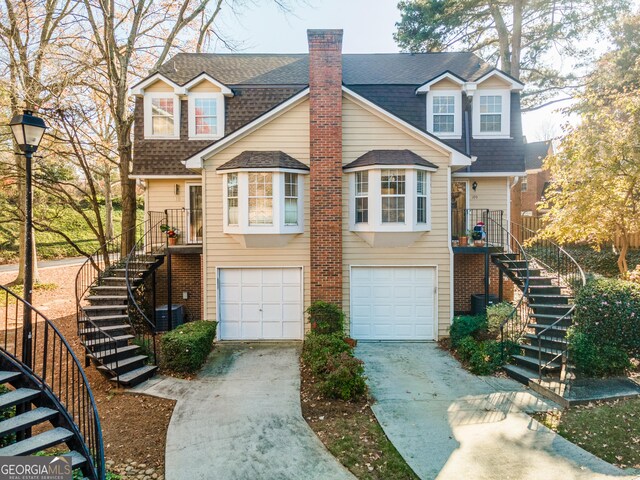 111 Swanton Hill Ct, Decatur, GA 30030 - view of front facade with concrete driveway, stairway, an attached garage, and a shingled roof