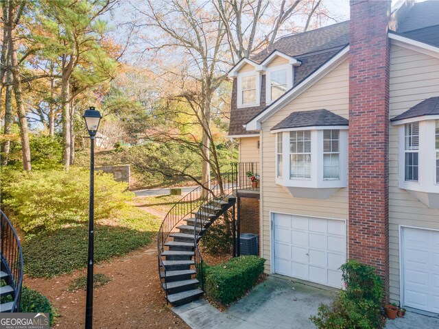 111 Swanton Hill Ct, Decatur, GA 30030 - view of property exterior with a shingled roof, stairs, concrete driveway, a garage, and central air condition unit