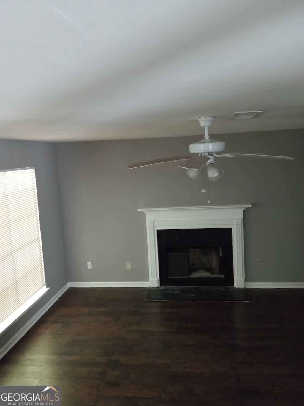 unfurnished living room with ceiling fan and dark hardwood / wood-style flooring