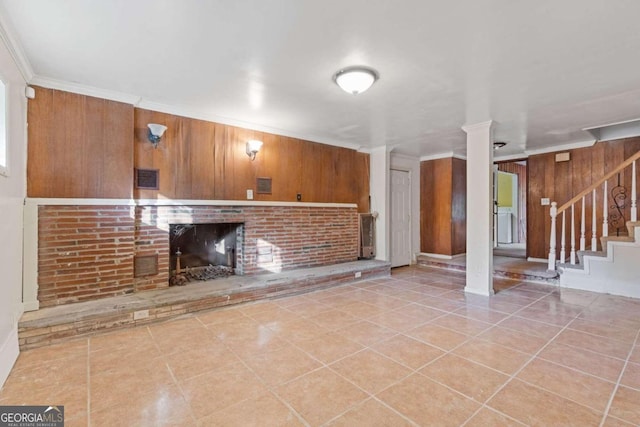 unfurnished living room with light tile patterned floors, crown molding, and wooden walls