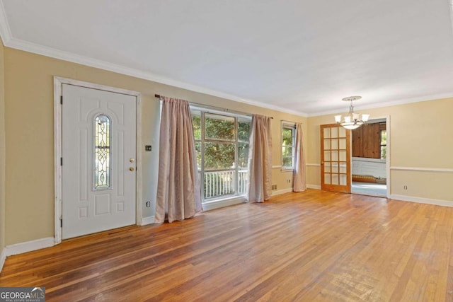 entrance foyer with a chandelier, wood-type flooring, and ornamental molding