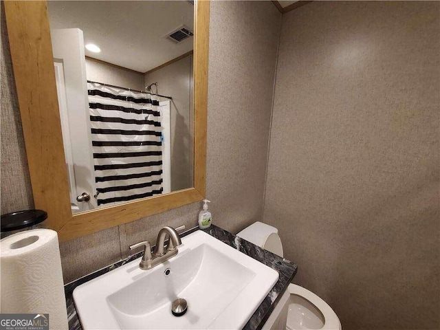 bathroom featuring a shower with shower curtain, toilet, and sink