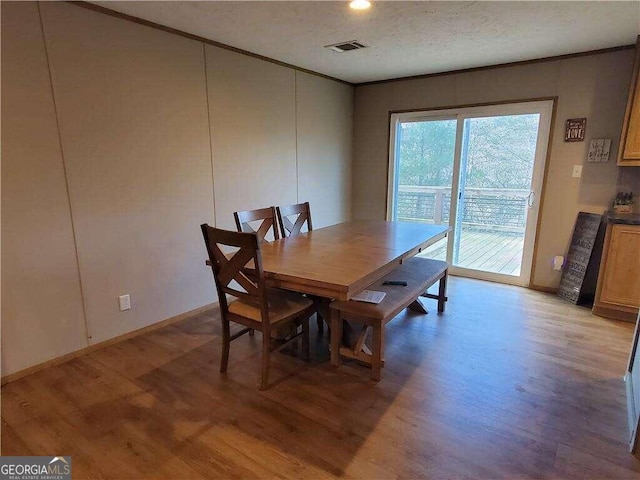 dining room with light wood-type flooring, a textured ceiling, and ornamental molding