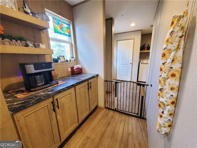 kitchen with washer / dryer, a textured ceiling, and light hardwood / wood-style floors