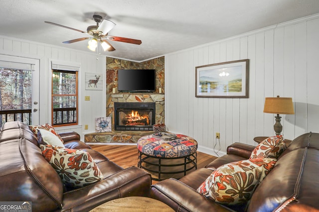 living room with hardwood / wood-style flooring, ceiling fan, wood walls, and a fireplace