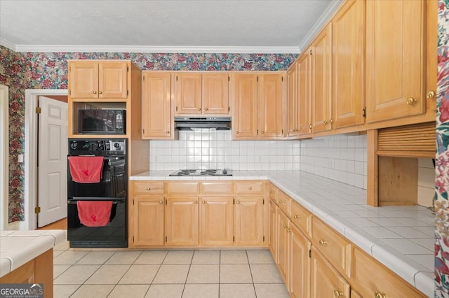 kitchen featuring tile counters, crown molding, light brown cabinetry, light tile patterned flooring, and black appliances