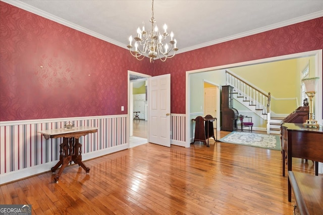 interior space with wood-type flooring, crown molding, and an inviting chandelier