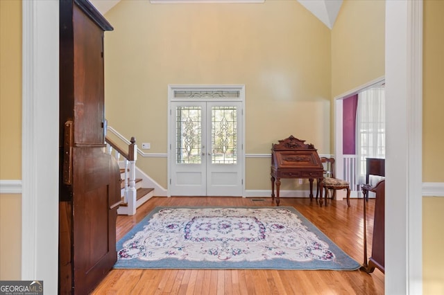 foyer entrance featuring french doors, high vaulted ceiling, and wood-type flooring