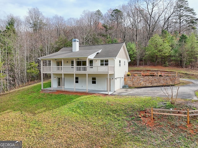 back of property with ceiling fan, a yard, a balcony, a garage, and a porch