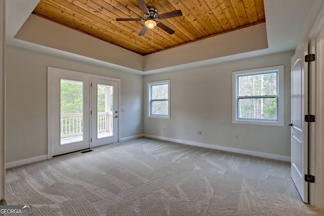 empty room with light colored carpet, ceiling fan, wooden ceiling, and a tray ceiling