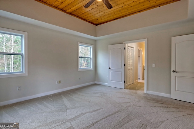 unfurnished bedroom with ceiling fan, wood ceiling, light carpet, and multiple windows