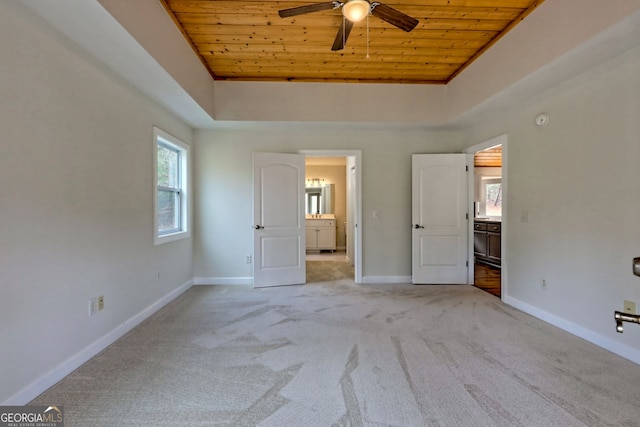 unfurnished bedroom featuring a raised ceiling, light carpet, ceiling fan, and wooden ceiling