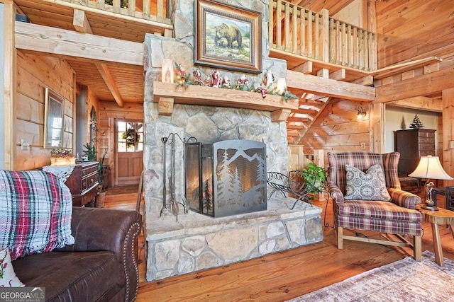 living room featuring wooden ceiling, hardwood / wood-style flooring, a stone fireplace, and wooden walls