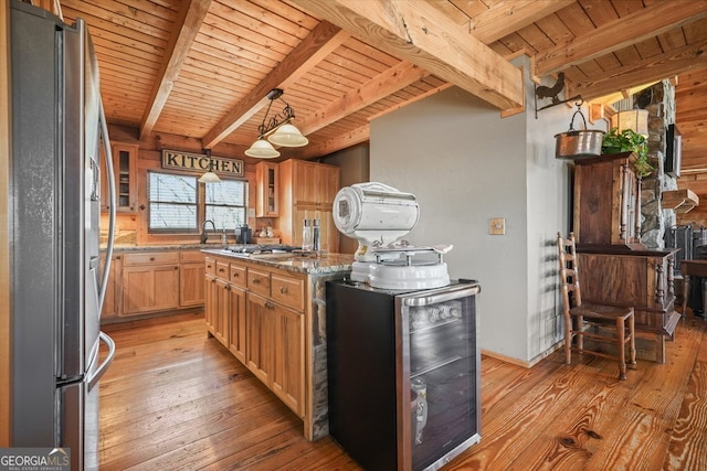 kitchen with light wood finished floors, wooden ceiling, glass insert cabinets, light stone counters, and freestanding refrigerator