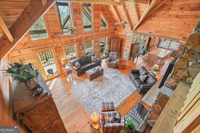 living room with wooden ceiling, wood walls, beamed ceiling, and ceiling fan