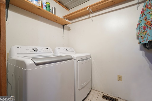 clothes washing area with laundry area, light tile patterned floors, visible vents, and washing machine and clothes dryer