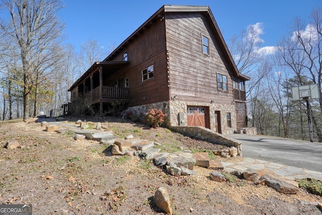 view of side of home featuring aphalt driveway and stone siding