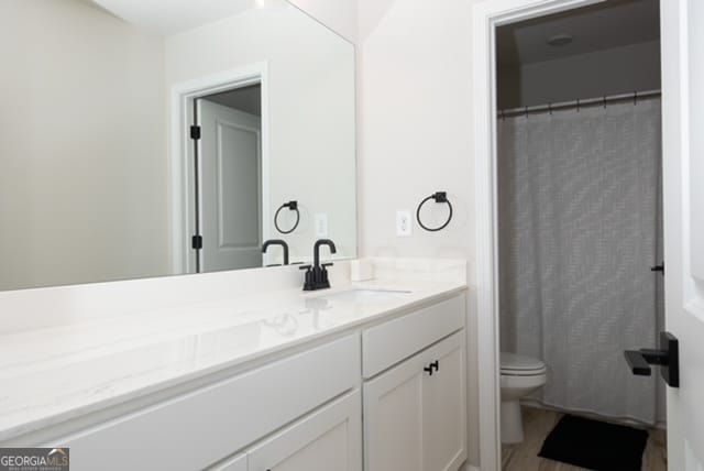 bathroom featuring a shower with curtain, vanity, and toilet