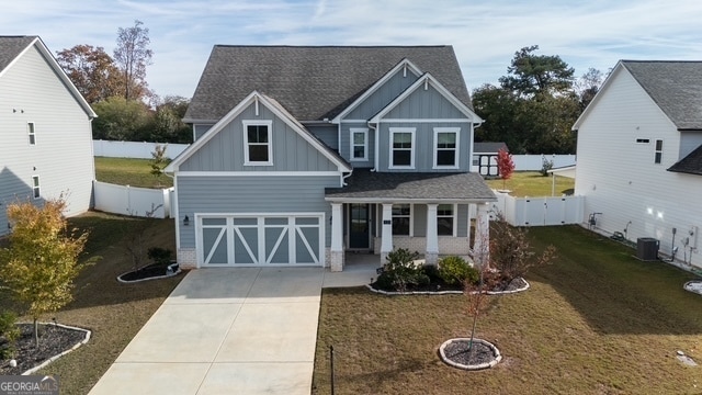 view of front of house with a porch, a garage, a front yard, and central AC