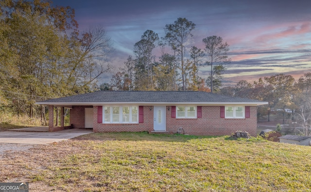 single story home featuring driveway, a yard, an attached carport, and brick siding