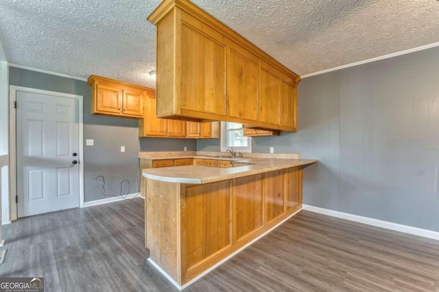 kitchen featuring dark hardwood / wood-style flooring, kitchen peninsula, and crown molding