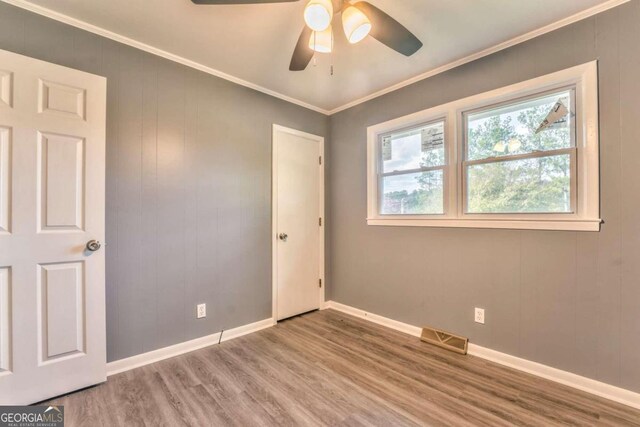 empty room with hardwood / wood-style floors, ceiling fan, and ornamental molding