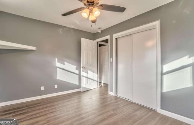 unfurnished bedroom with ceiling fan, a closet, and hardwood / wood-style flooring