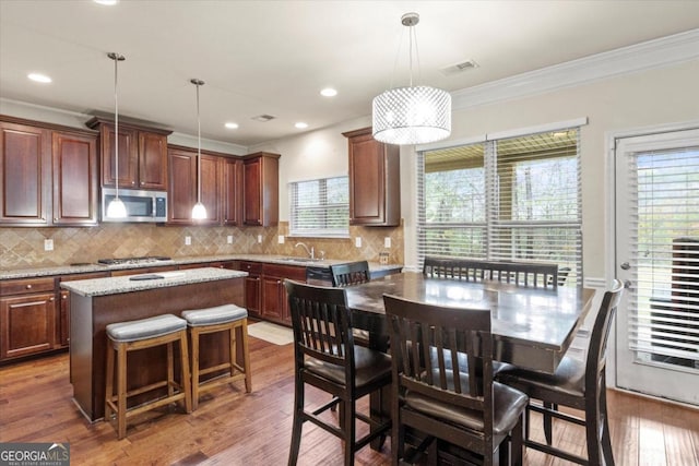 kitchen with sink, hanging light fixtures, dark hardwood / wood-style floors, a kitchen island, and appliances with stainless steel finishes