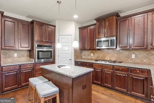 kitchen featuring backsplash, light stone counters, stainless steel appliances, and light hardwood / wood-style floors