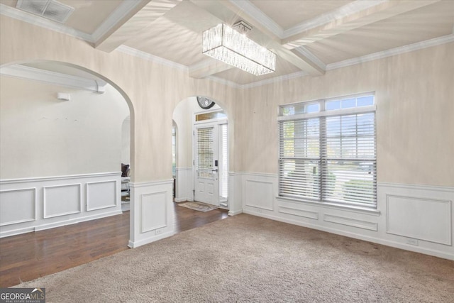 spare room with beamed ceiling, a notable chandelier, ornamental molding, and dark wood-type flooring