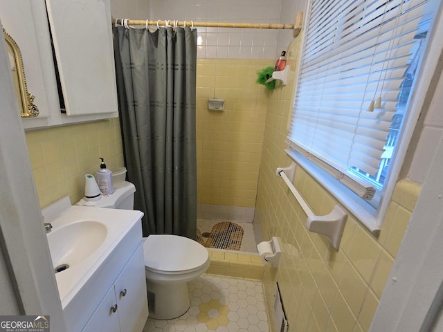 bathroom featuring walk in shower, tile patterned floors, toilet, vanity, and tile walls