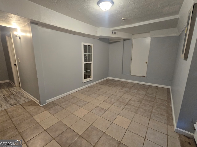 spare room with light tile patterned floors and a textured ceiling