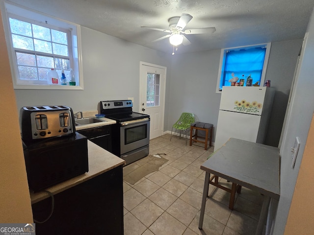 kitchen featuring stainless steel range with electric stovetop, white refrigerator, sink, ceiling fan, and light tile patterned floors