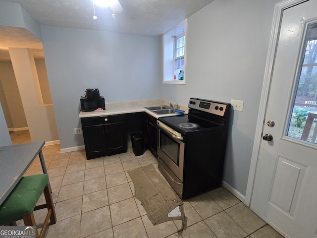 kitchen featuring electric range, ceiling fan, light tile patterned floors, and sink