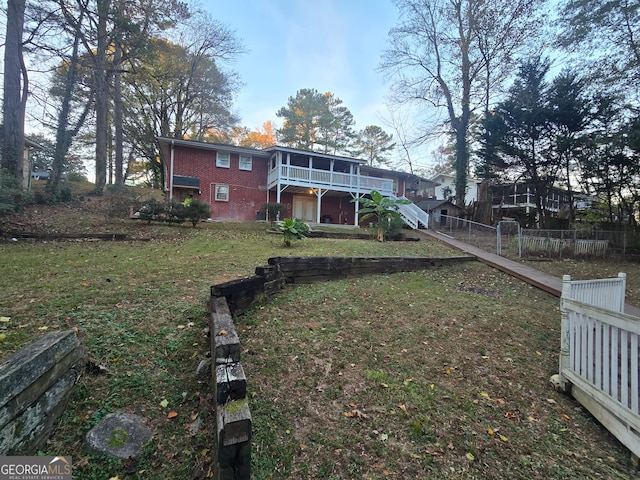 exterior space featuring a lawn, a sunroom, and a deck