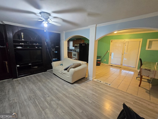 living room featuring wood-type flooring, ceiling fan, and crown molding