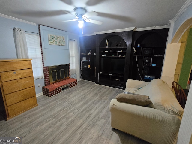 sitting room with ceiling fan, a fireplace, ornamental molding, and hardwood / wood-style flooring