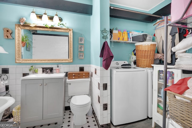 bathroom with vanity, washer / clothes dryer, toilet, and tile walls