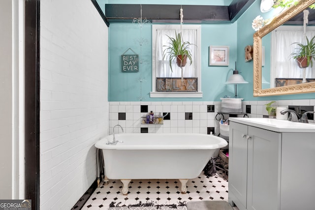 bathroom featuring a bathtub, vanity, brick wall, and tile walls