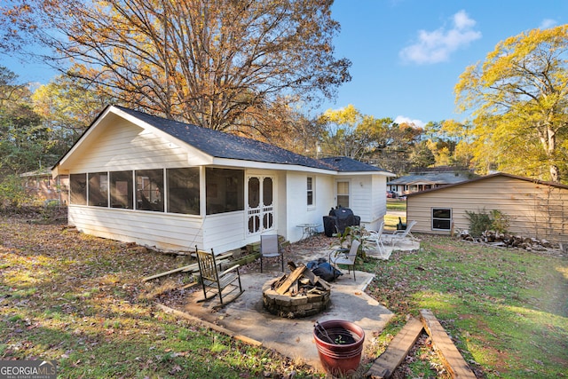 rear view of property featuring a patio, an outdoor fire pit, and a sunroom