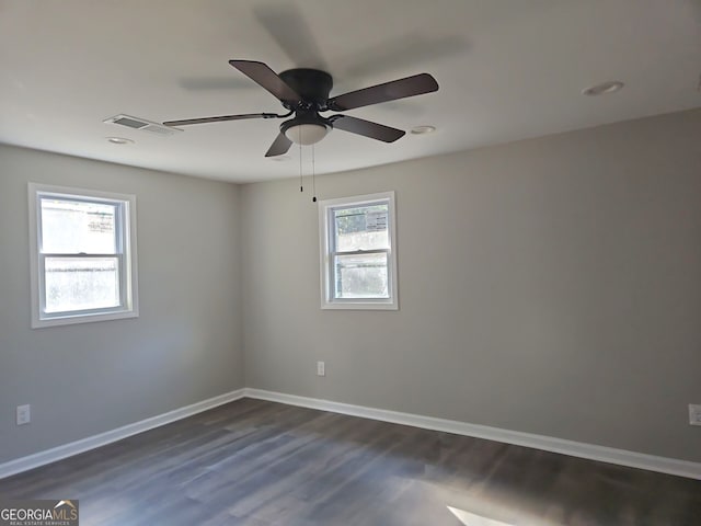 empty room with ceiling fan, dark wood-type flooring, and a wealth of natural light