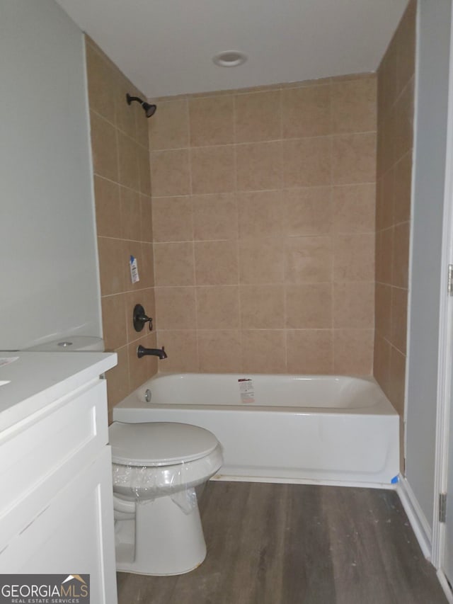 full bathroom featuring vanity, wood-type flooring, tiled shower / bath combo, and toilet