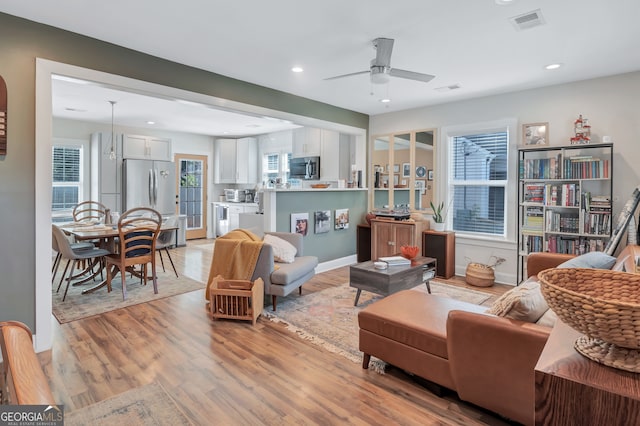 living room with light wood-type flooring and ceiling fan