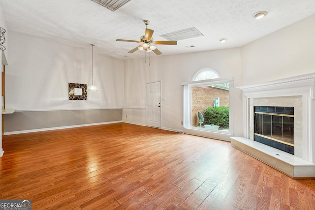 unfurnished living room with a high end fireplace, wood-type flooring, a textured ceiling, and ceiling fan