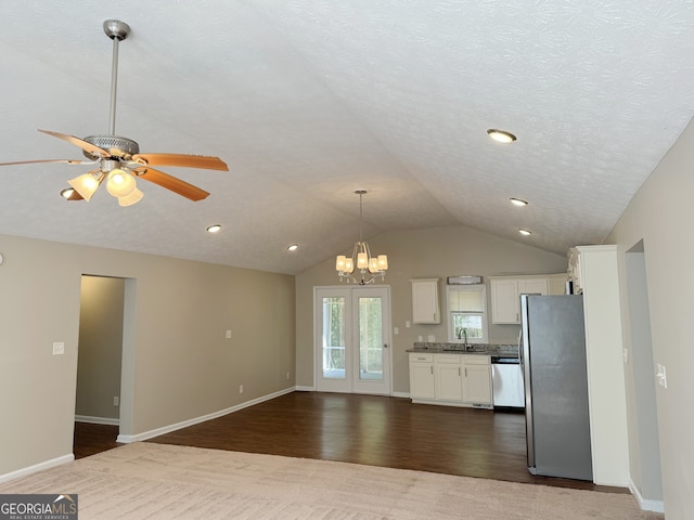 kitchen featuring dark wood-type flooring, vaulted ceiling, white cabinets, ceiling fan with notable chandelier, and appliances with stainless steel finishes