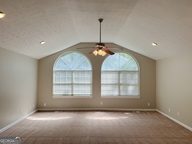 carpeted spare room featuring a textured ceiling, ceiling fan, and lofted ceiling