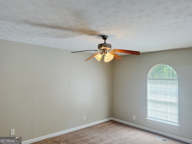 carpeted spare room featuring ceiling fan and a textured ceiling