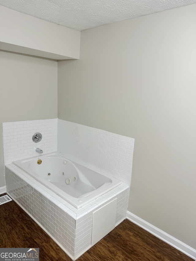 bathroom featuring tiled bath, a textured ceiling, and hardwood / wood-style flooring