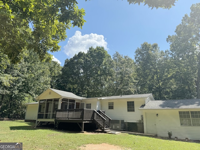 back of property with a sunroom, a deck, and a lawn